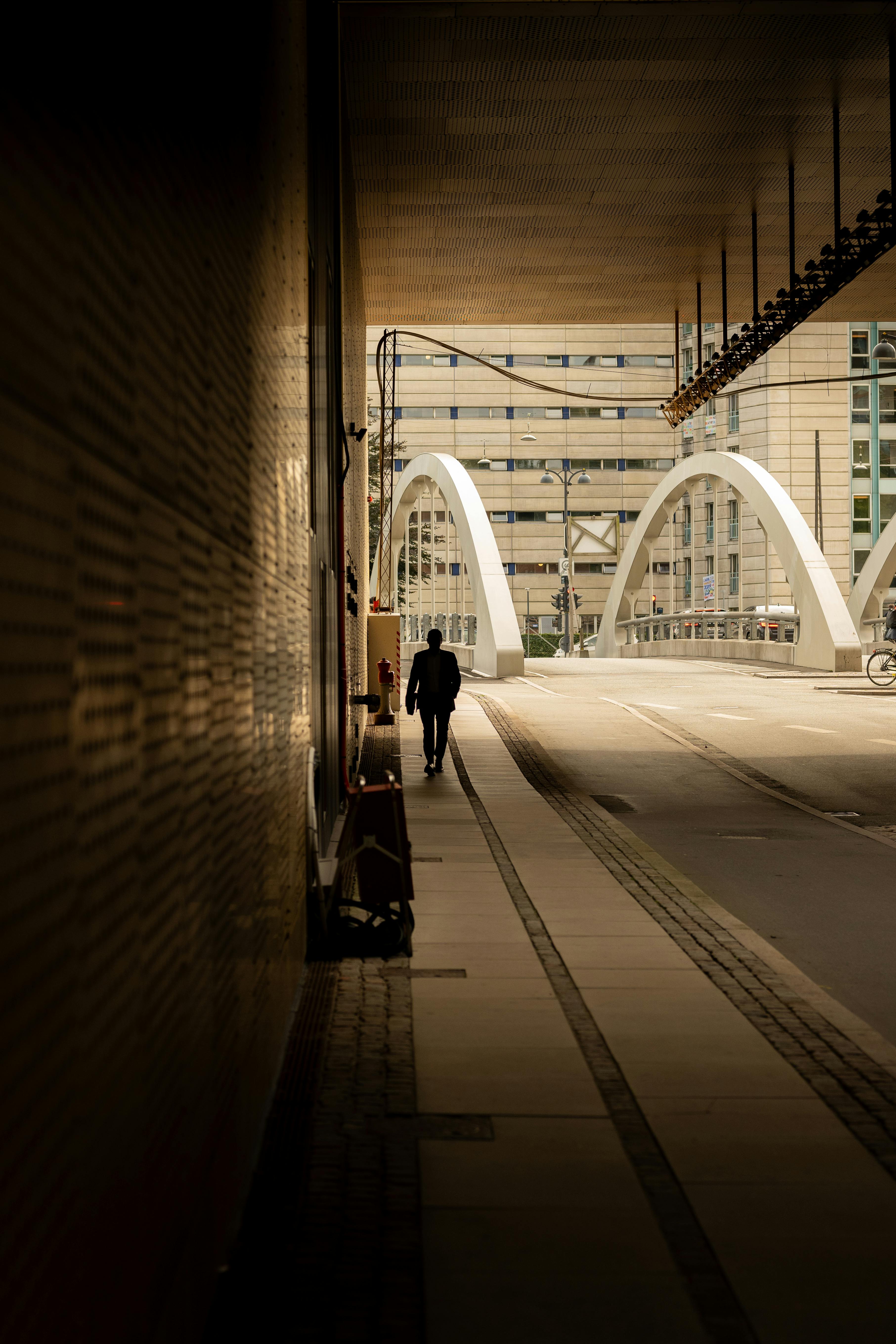 A man walks on a bridge in Copenhagen, Denmark, creating a striking urban silhouette.