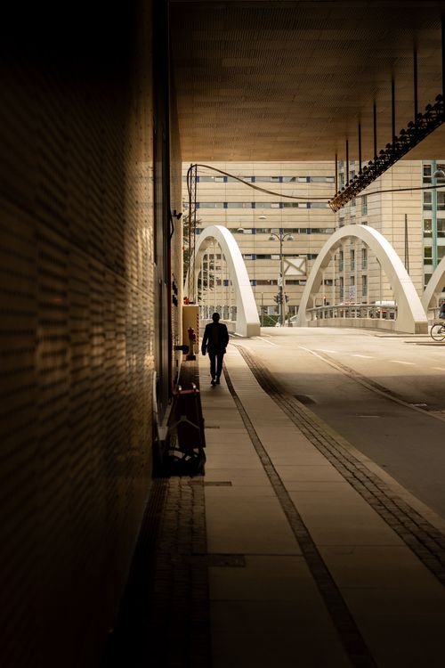 Free A man walks on a bridge in Copenhagen, Denmark, creating a striking urban silhouette. Stock Photo
