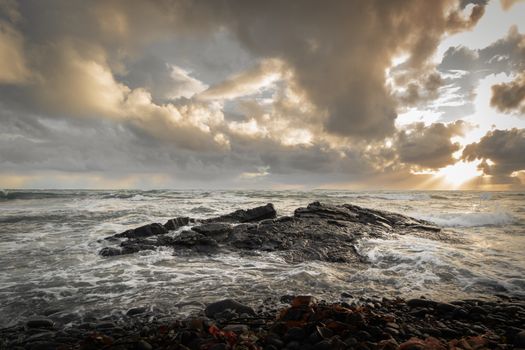 Captivating seascape in Þorlákshöfn, Iceland, showcasing dramatic clouds and rocky shoreline at sunset.