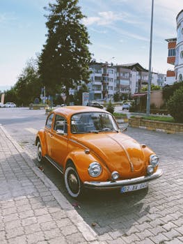 A classic orange Volkswagen Beetle parked on a city street in Nazilli, Türkiye.