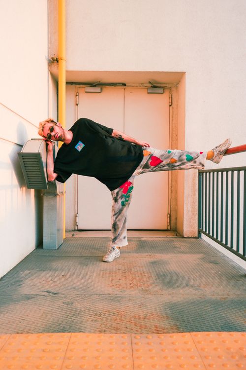 Free A trendy man poses creatively outdoors, showcasing his artistic style and urban fashion sense. Stock Photo