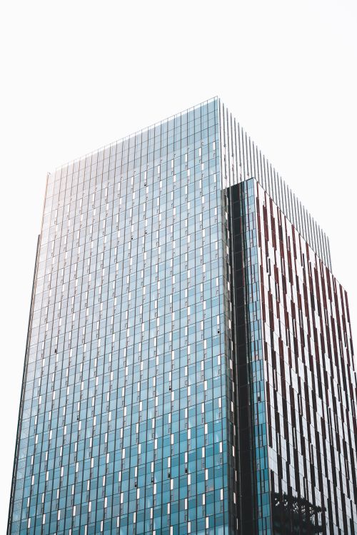Free Spectacular shot of a modern office skyscraper with sleek glass facade and geometric design elements. Ideal for urban architecture themes. Stock Photo