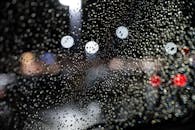 夜晚，挡风玻璃上清晰的雨滴映衬着背景中彩色的散景灯光