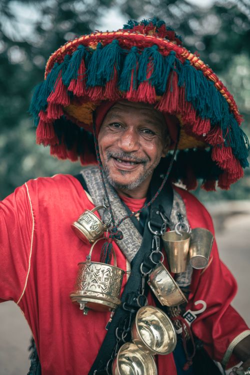 Free Smiling man in vibrant traditional clothing with decorated hat and cups outdoors. Stock Photo