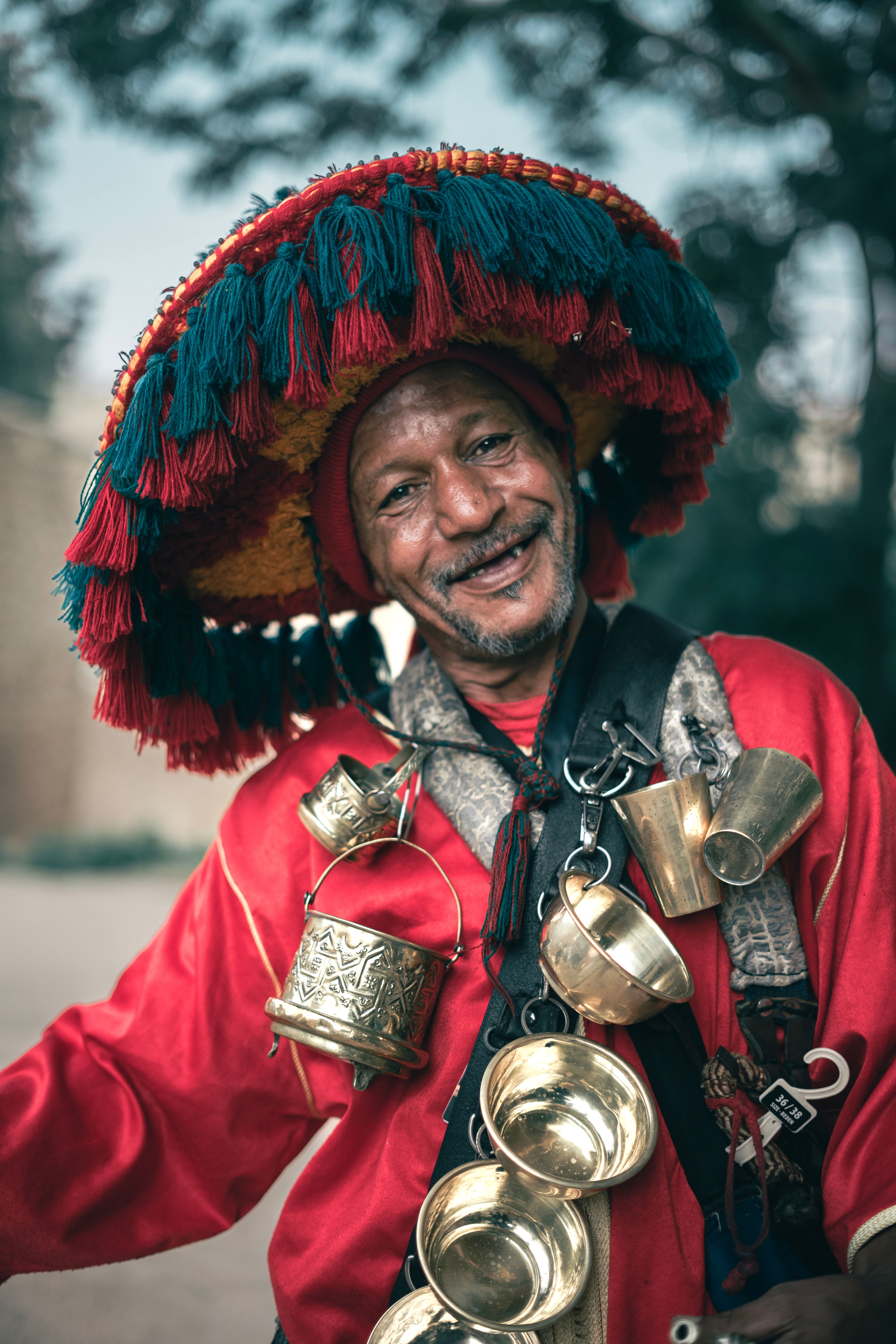 Portrait of an elderly Moroccan man in traditional clothing with a decorative hat and metallic ornaments.