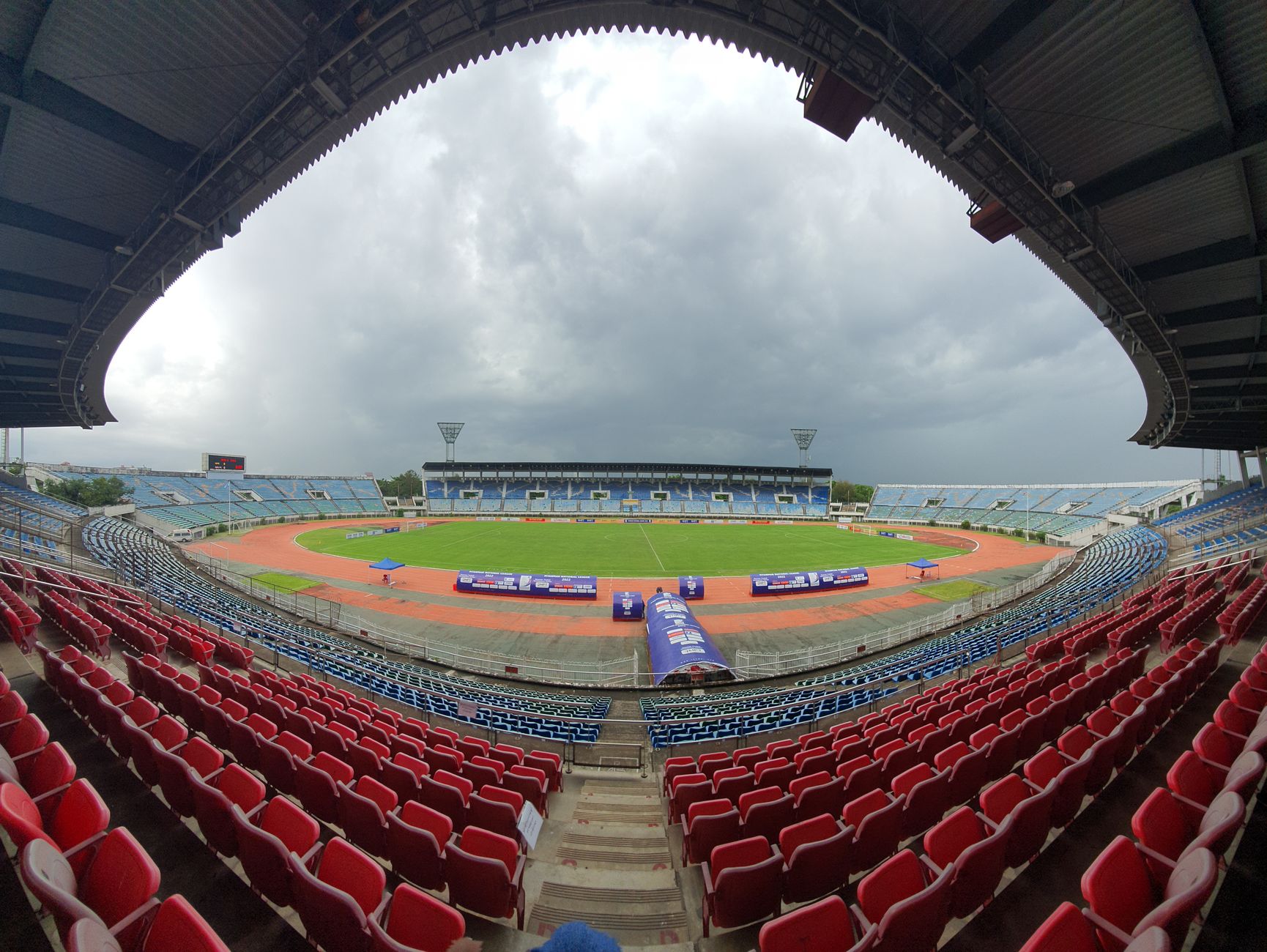 Wide-angle view of a sports stadium in Yangon, Myanmar with rain clouds overhead.