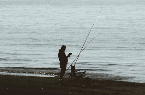 Angler with Fishing Rods Set on the Beach at Dusk