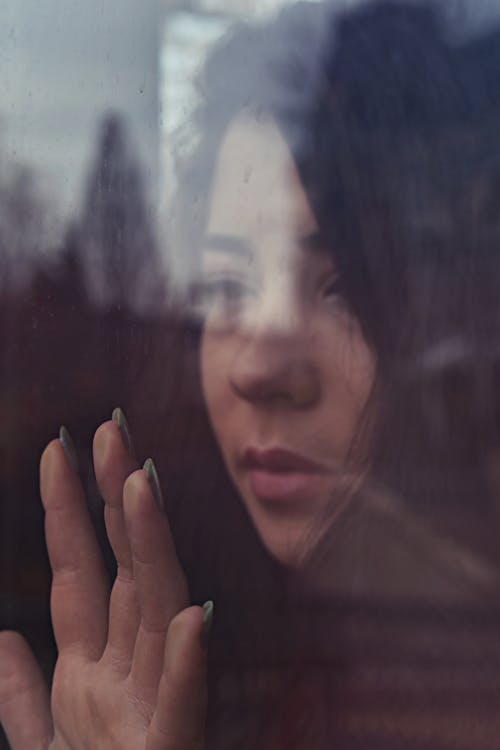 Shallow Focus Photo of Woman Touching Window