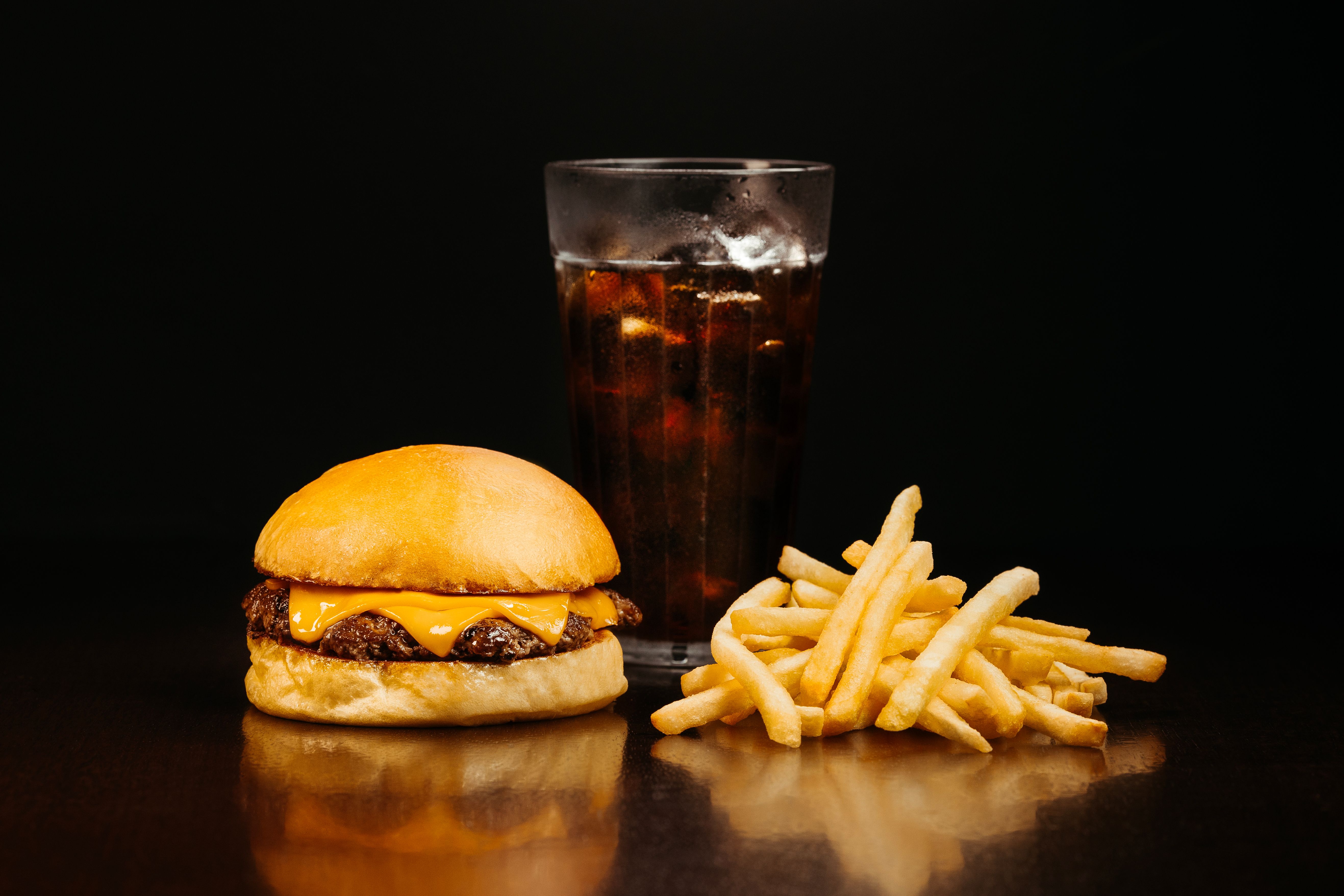 A cheeseburger and french fries lit warm against a dark background