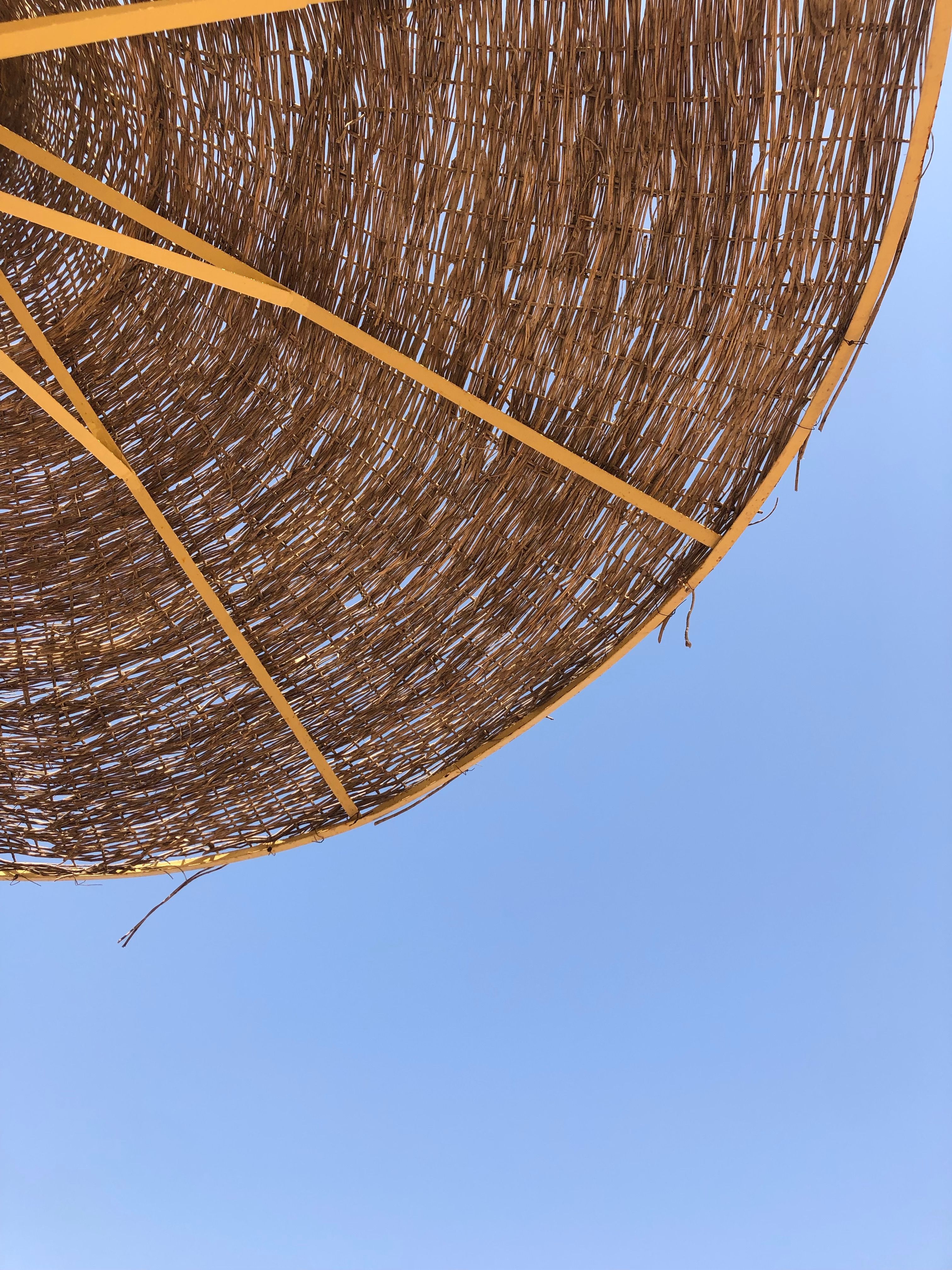 A woven beach umbrella under a clear sky in Sharm El-Sheikh, Egypt, capturing sunny vibes.