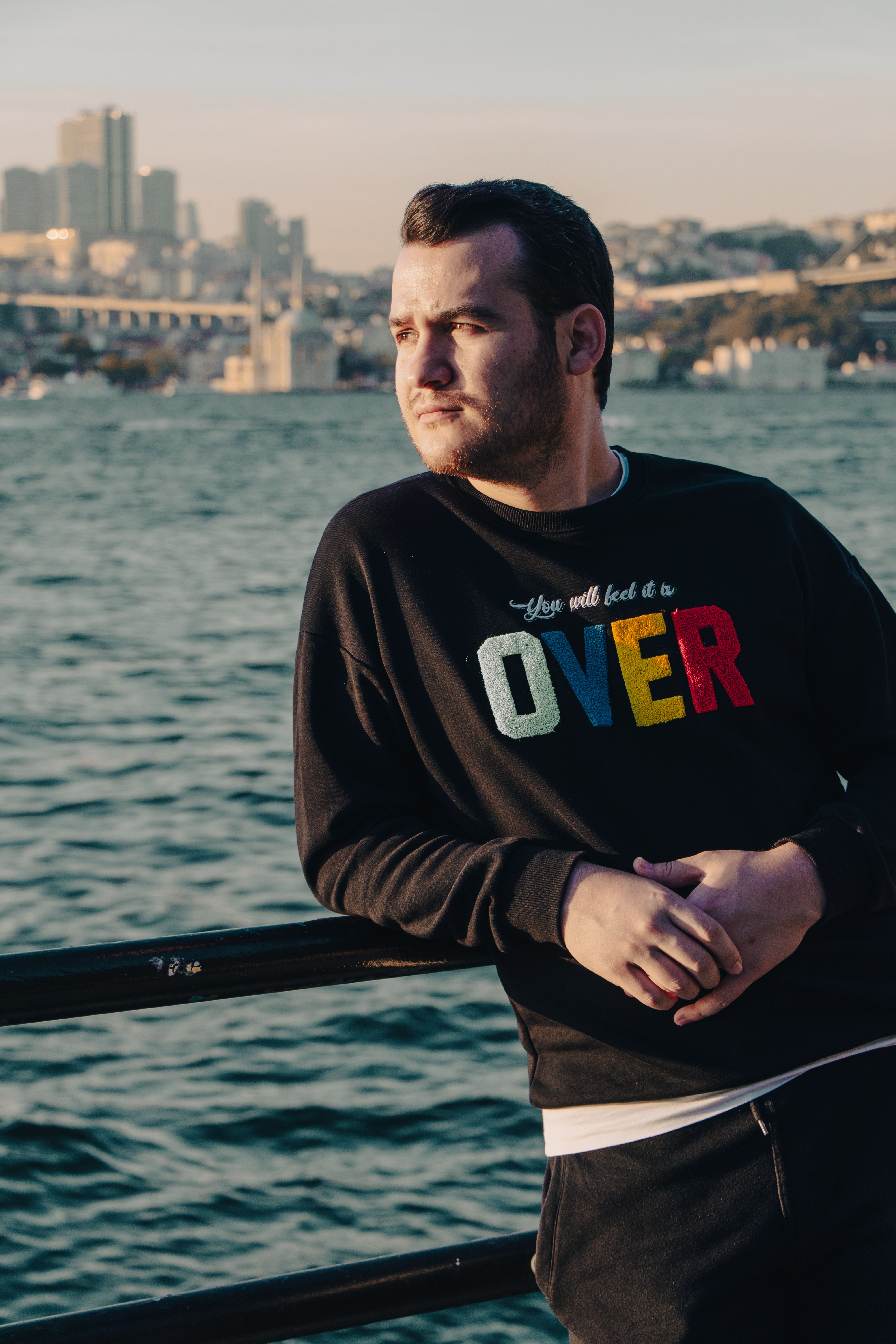Man leaning on railing with Bosphorus Bridge in background, Istanbul.