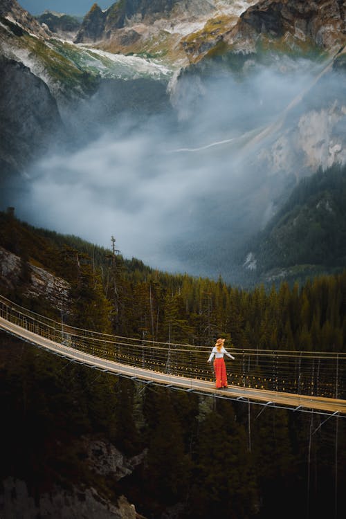 Woman Standing on Footbridge over Abyss in Mountains