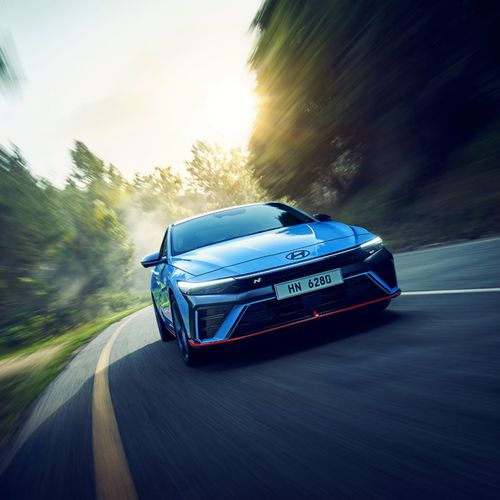 Free Blue sports car speeding on a curved road through a forest, showcasing motion blur. Stock Photo