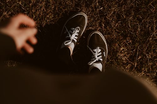 Free A pair of black sneakers on dry grass at daytime, capturing a casual, outdoor fashion vibe. Stock Photo