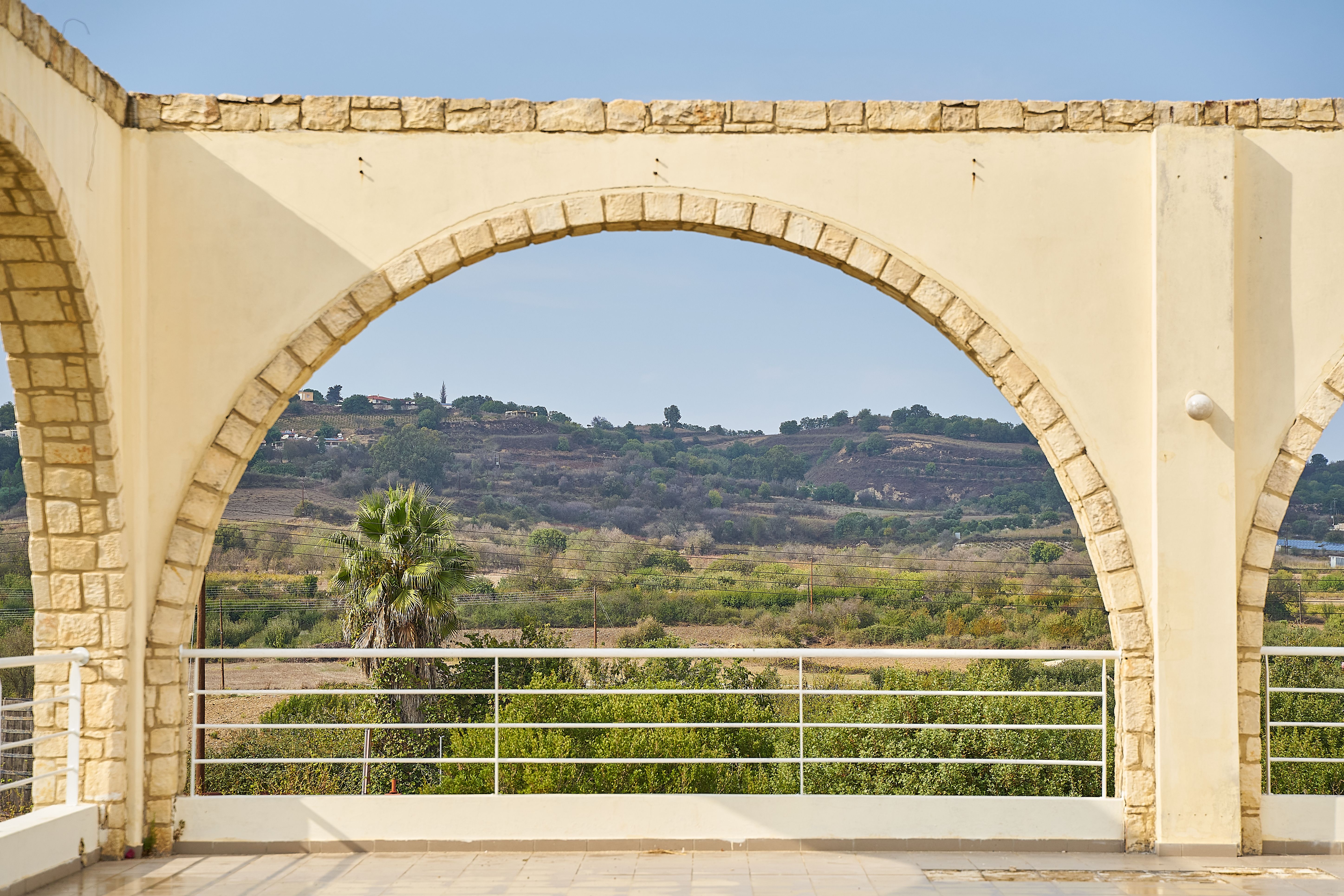 Arch and Railing with Trees and Hill behind · Free Stock Photo