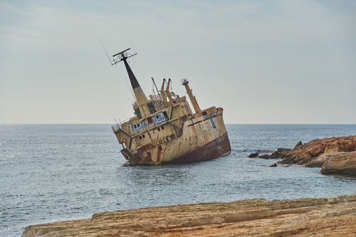 Free Rusting shipwreck stranded on rocky shoreline creating an eerie seascape scene. Stock Photo