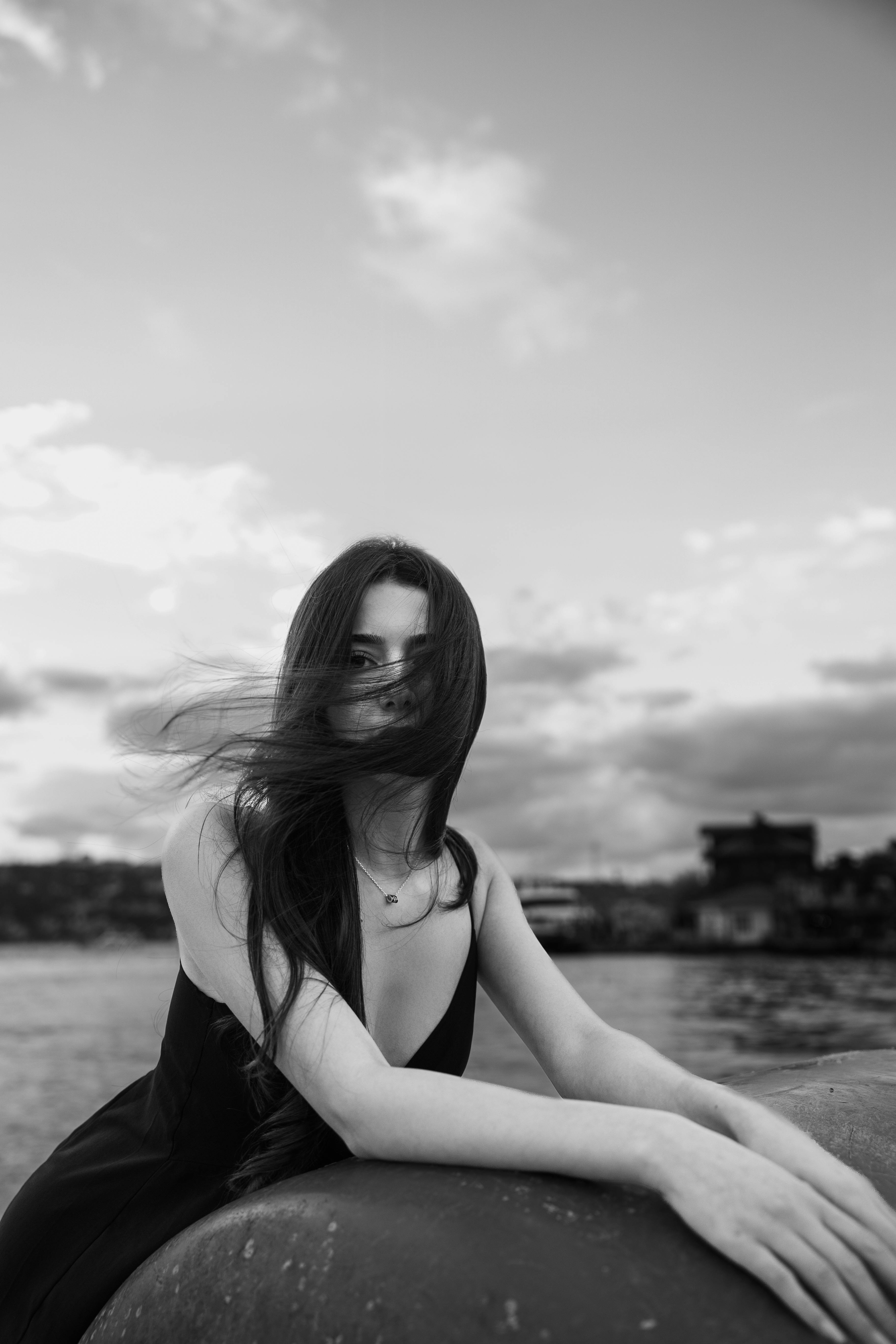 a woman sitting on a rock by the water