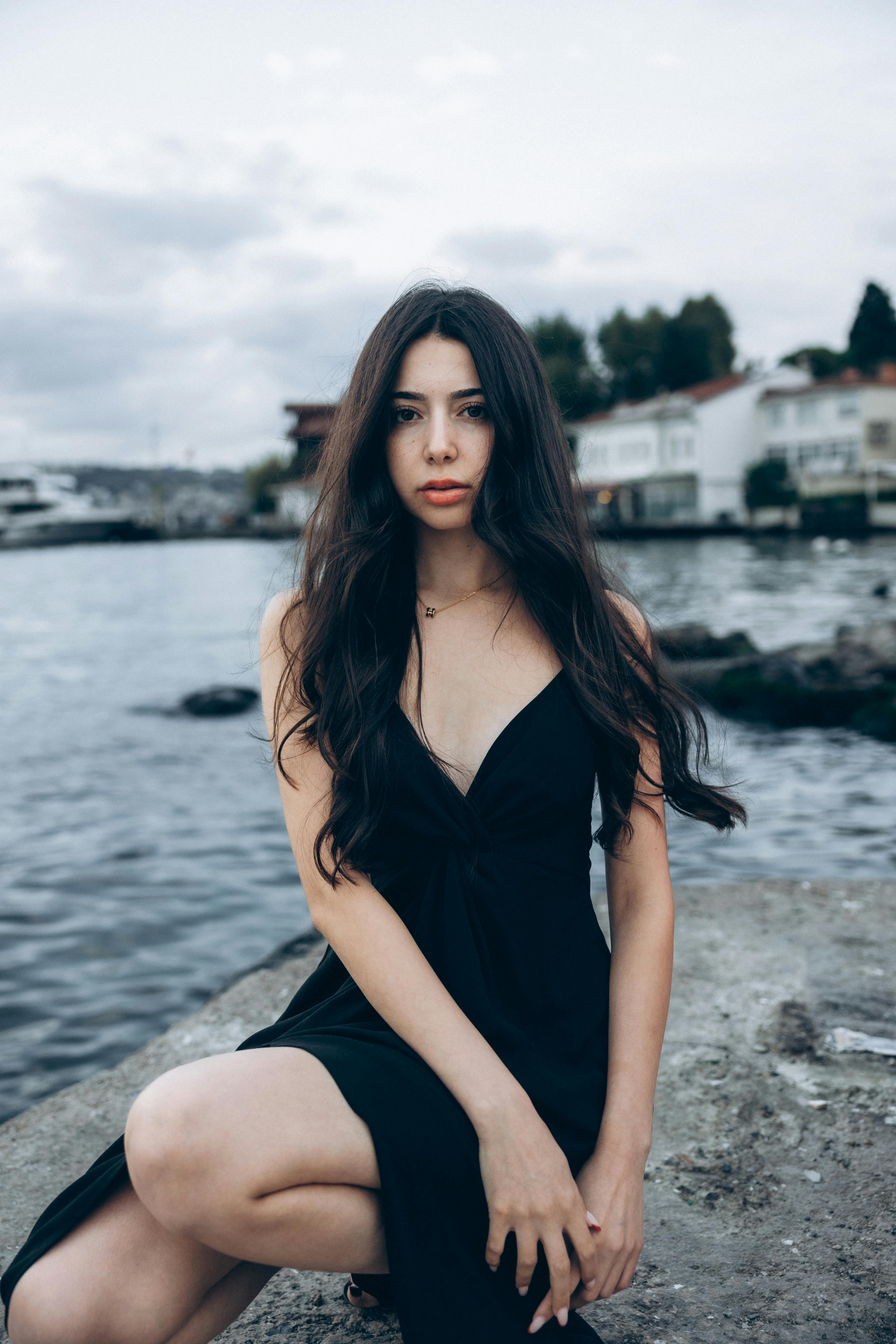 a woman in a black dress sitting on the rocks