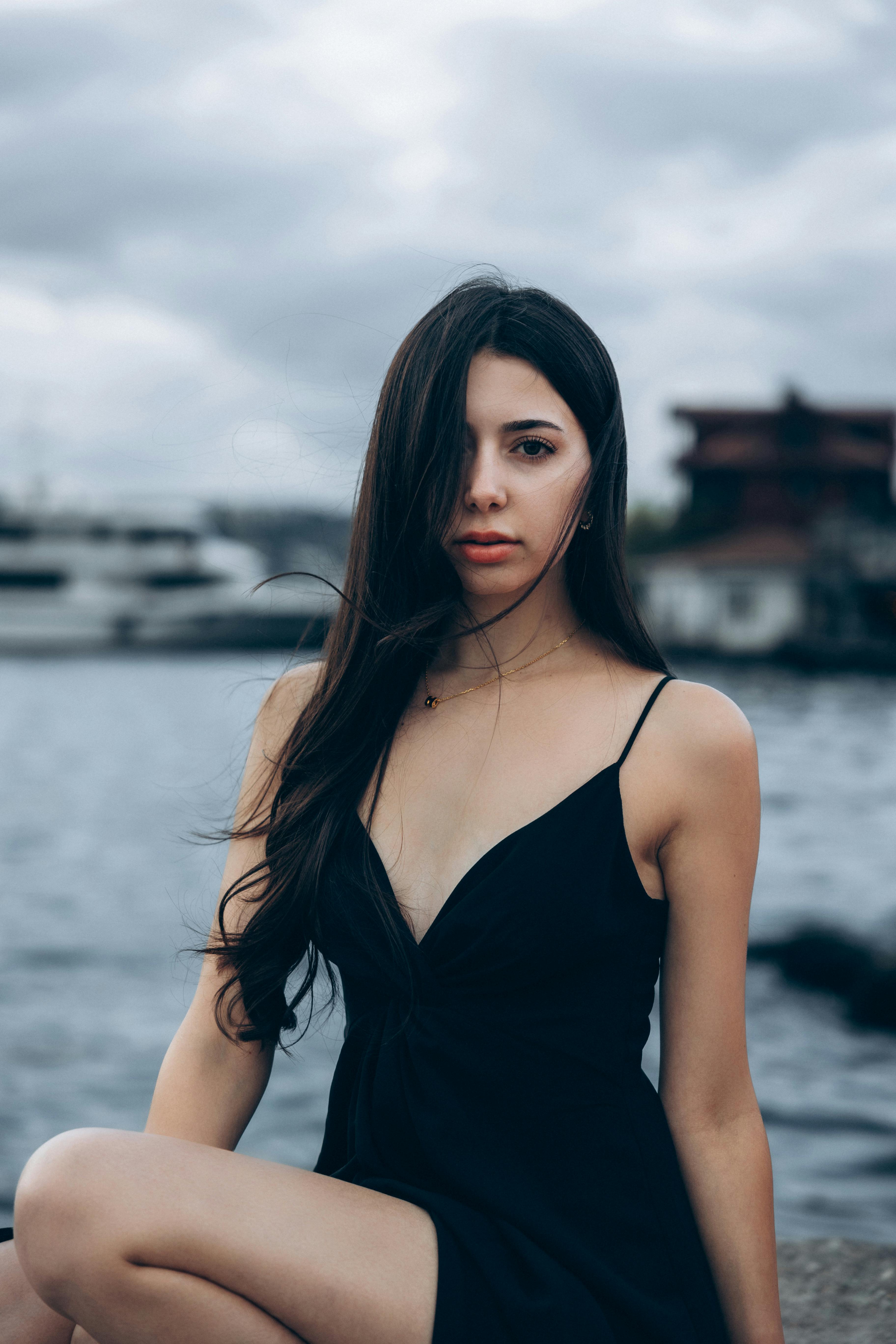 a woman in a black dress sitting on a dock