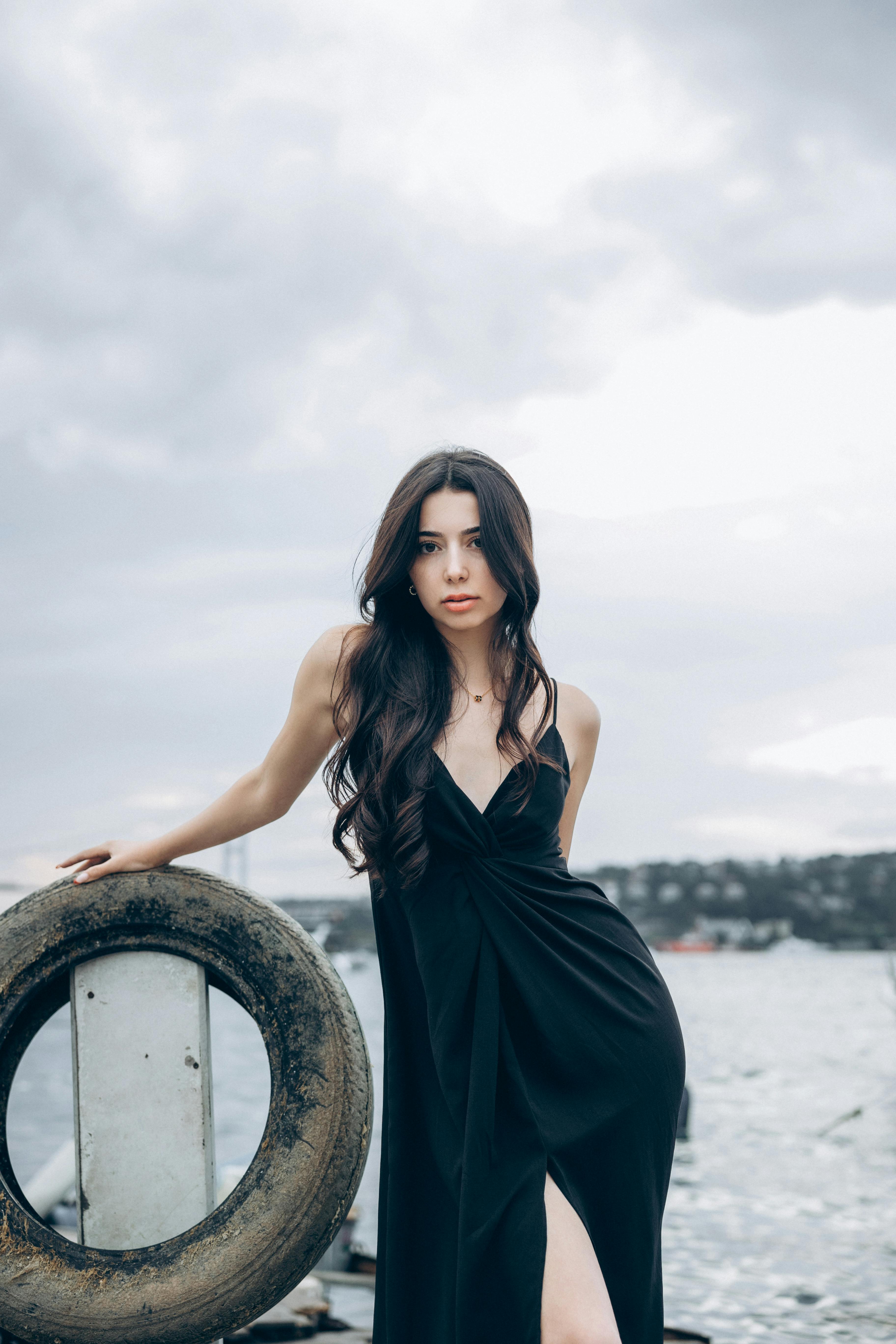 a woman in a black dress posing near a boat