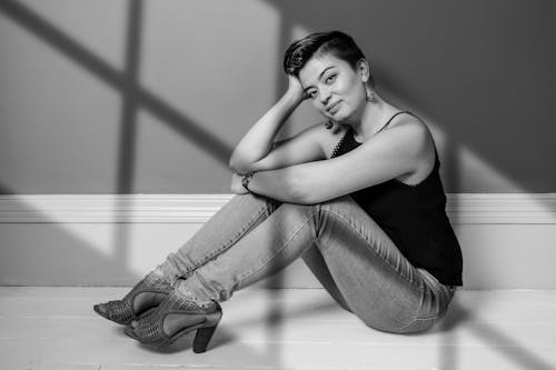 Young Woman in Jeans, Tank Top and Hills Sitting on the Floor 