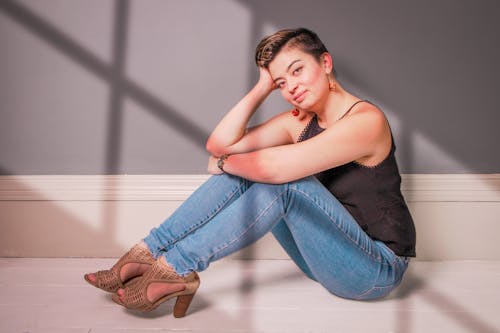 Brunette Woman in Black Tank Top and Jeans Posing on Floor