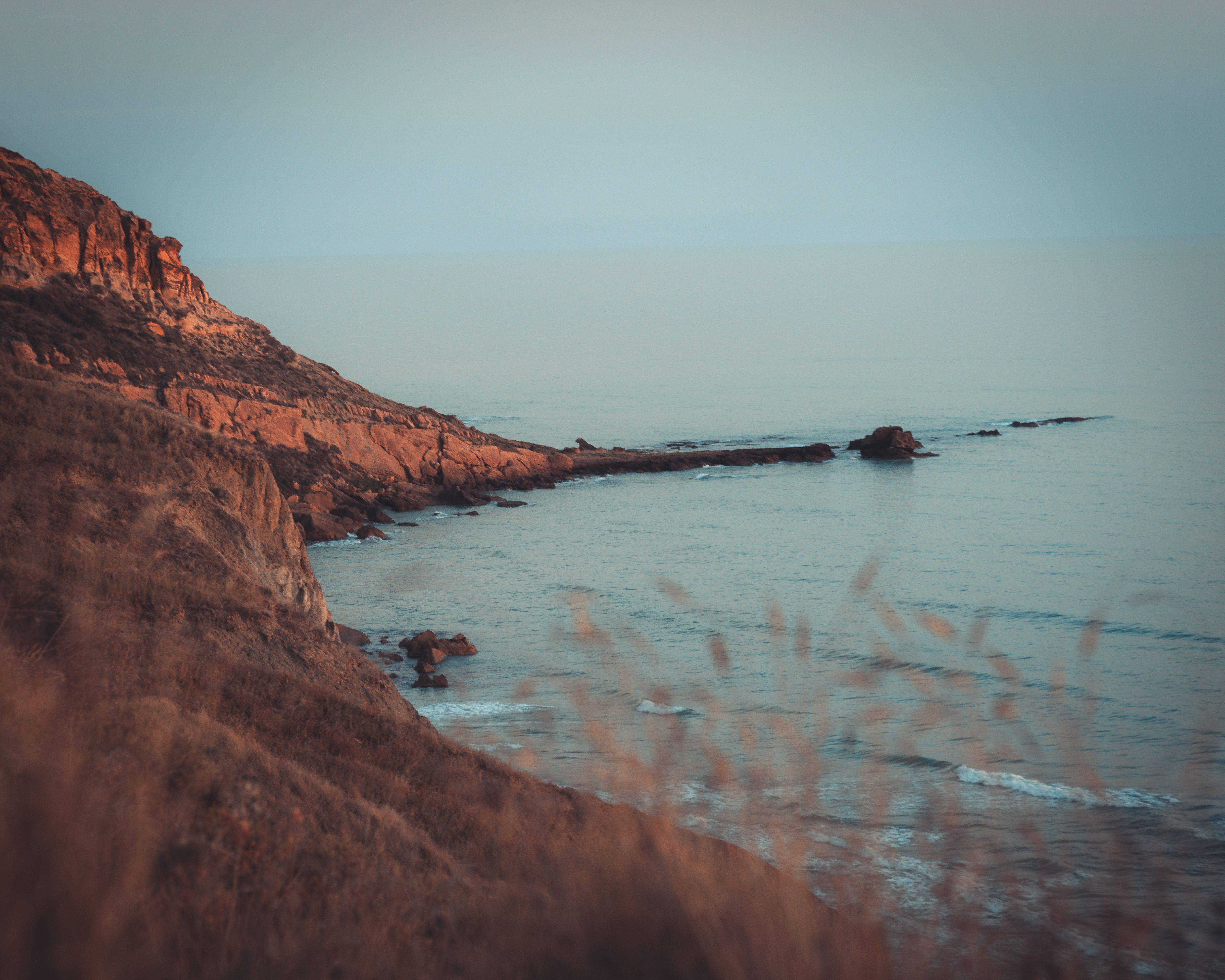 Tranquil coastal scene with rocky cliffs and calm sea at Sicilì, Italy.