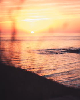 Capture the serene beauty of a peaceful sunrise over the ocean with gentle waves and vibrant colors.