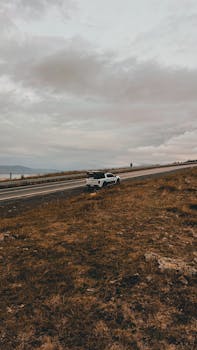 A pickup truck parked on a remote highway in Çıldır, Ardahan, Türkiye, under a cloudy sky.