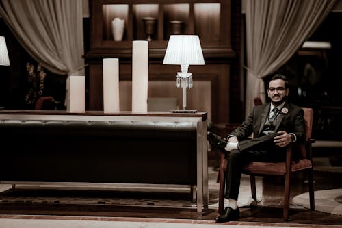 Groom in Black Suit Sitting on Armchair