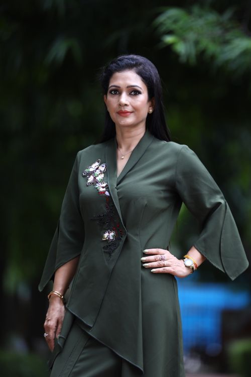 Free Portrait of a stylish woman posing in green attire with hand on hip, outdoors. Stock Photo