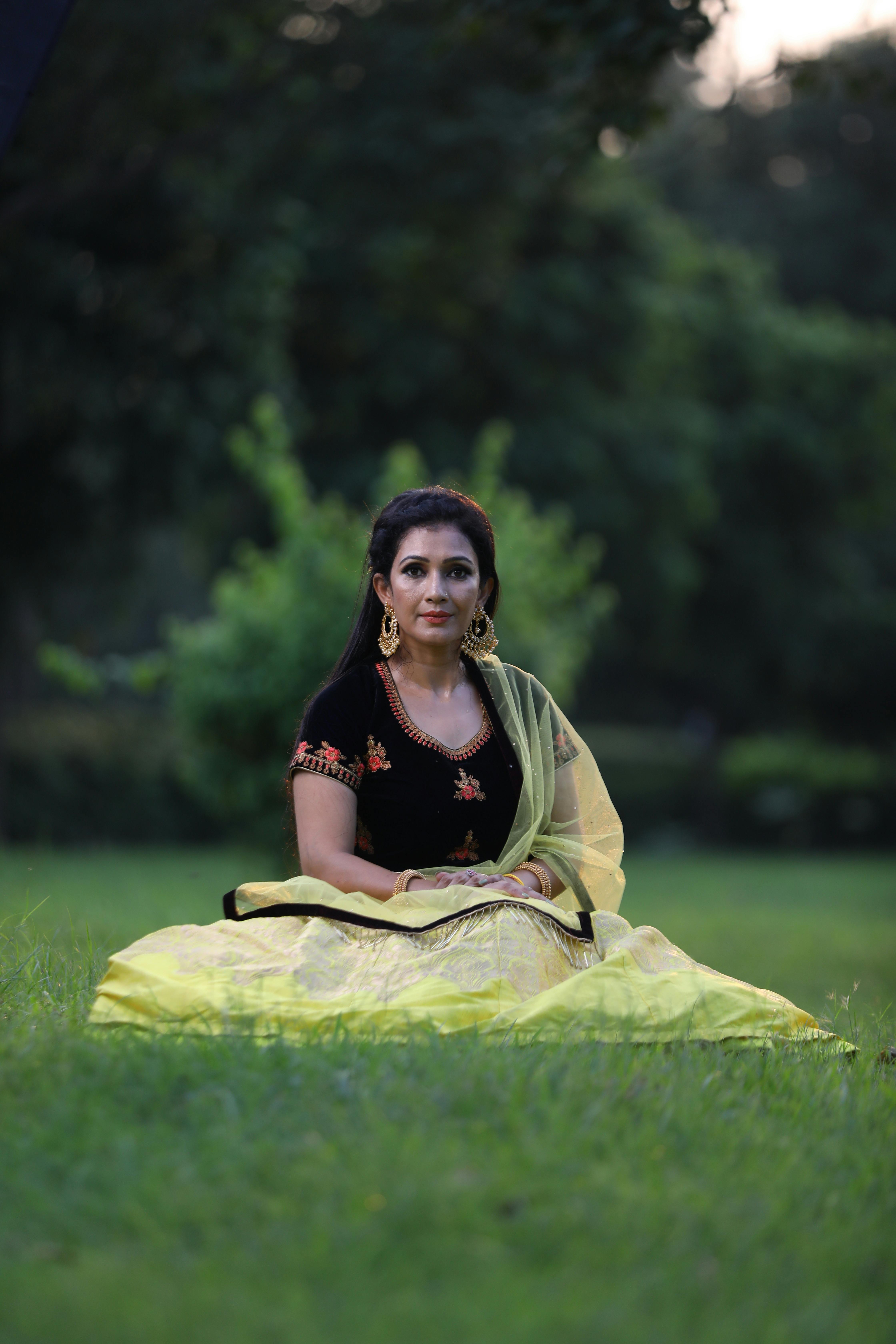 smiling beautiful girl sitting on green grass in park and looking at camera  Stock Photo - Alamy