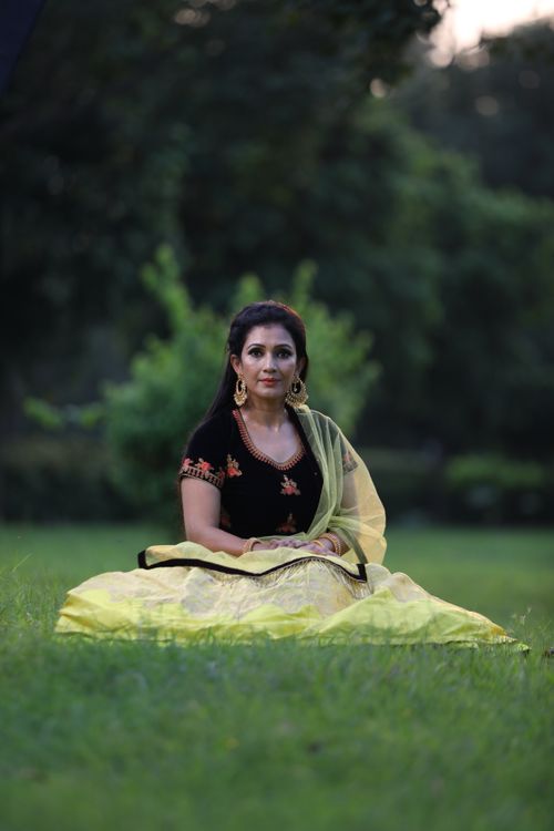 Free Woman in traditional clothing sitting on grass, embodying rural elegance and fashion. Stock Photo