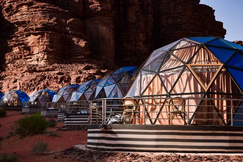 Free A row of geodesic dome cabins against a dramatic rocky desert backdrop. Stock Photo