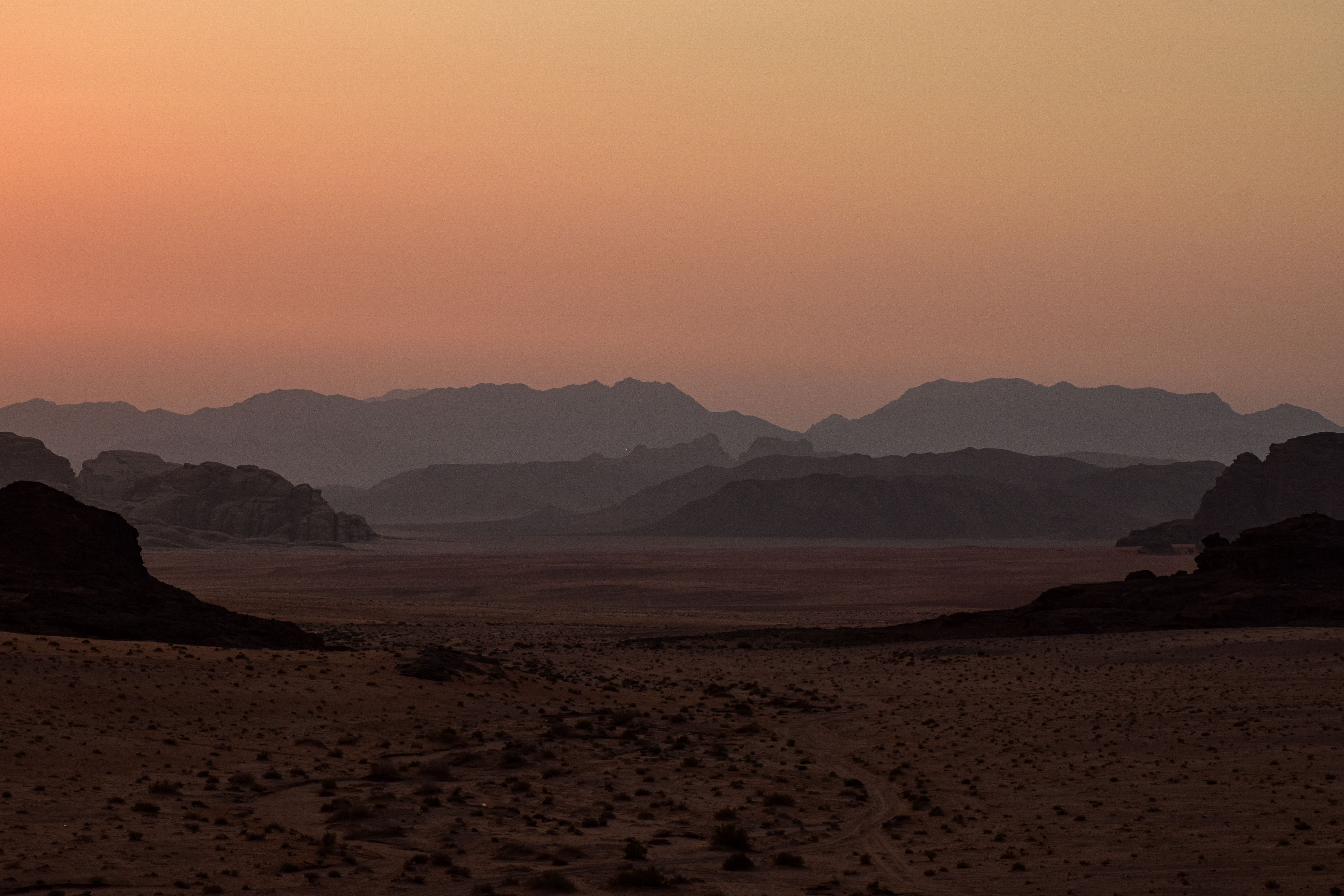 Breathtaking view of Wadi Rum desert at twilight with silhouetted mountain ranges.