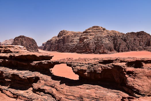 Explore the stunning rock formations of Wadi Rum desert, showcasing natural beauty under a clear blue sky.