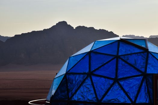 Geodesic blue dome in Wadi Rum desert with stunning mountain backdrop, perfect for luxury glamping.