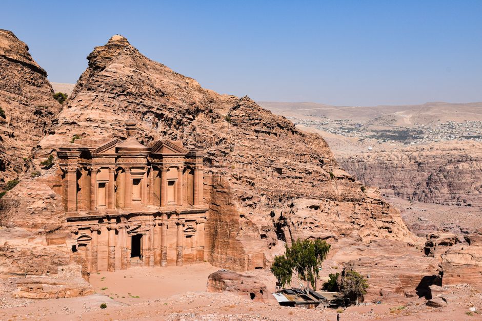 A Jordan Pass booklet with Petra in the background, symbolizing cost savings for travelers in Jordan