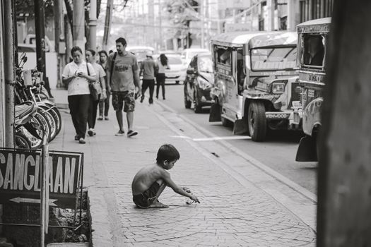 A child plays on a bustling city sidewalk, surrounded by urban life and people.