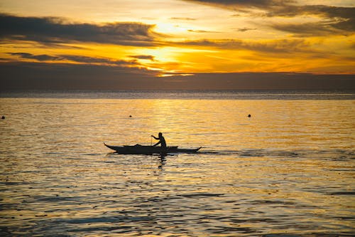 Man on Boat on Sea at Sunset