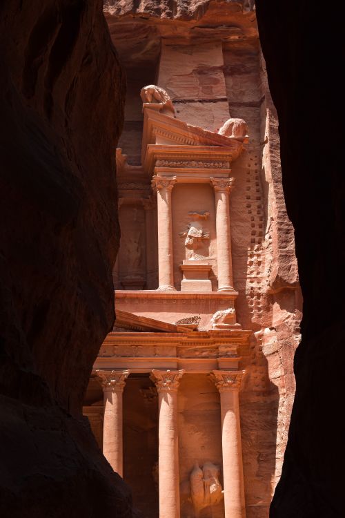 Free The iconic facade of the Treasury in Petra, seen through a canyon. A stunning example of ancient architecture. Stock Photo