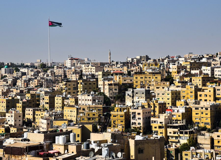 A panoramic view of Amman's densely packed buildings and a prominently flying flag.