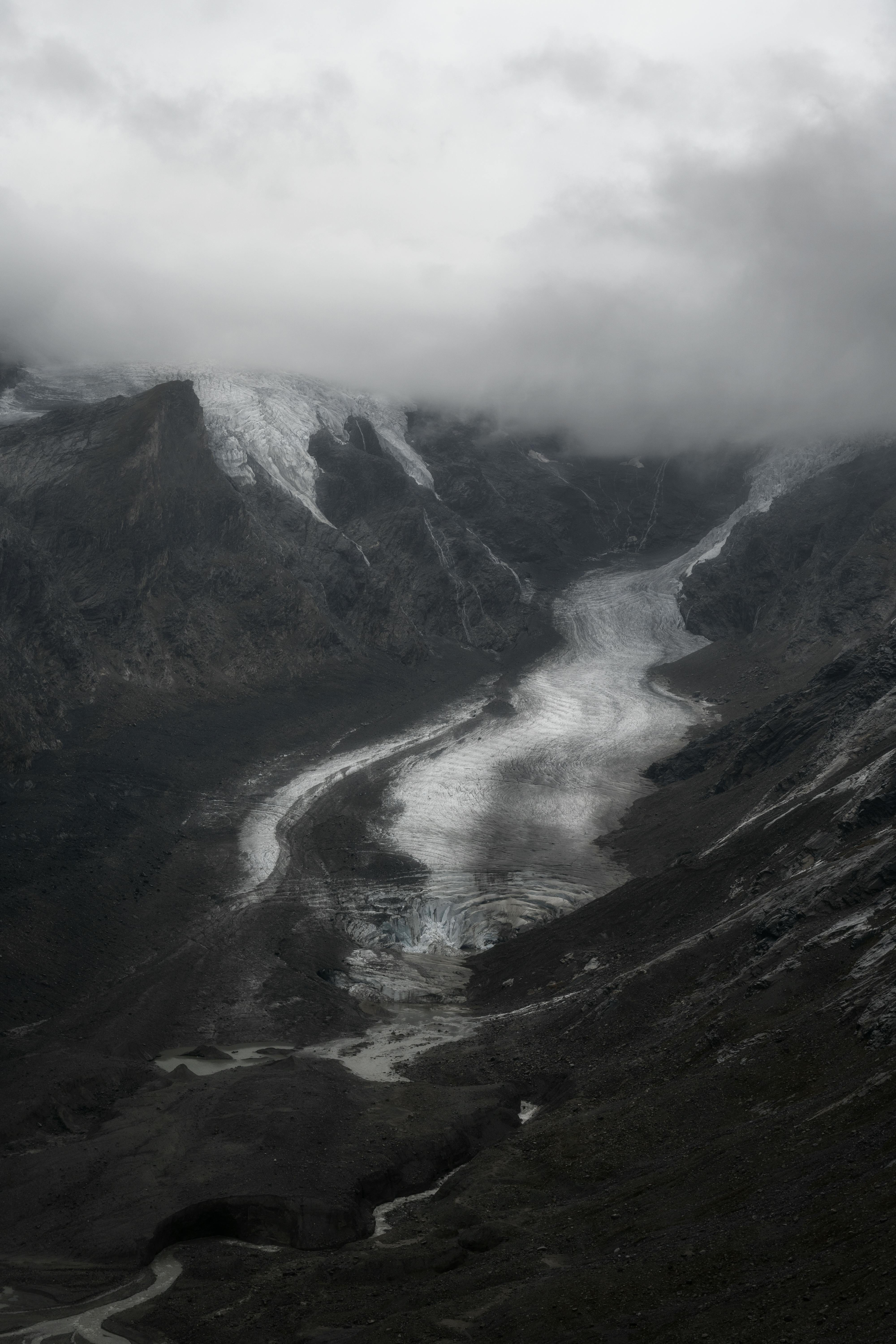 Moody view of a river cutting through the cloudy Ötztal Alps valley.