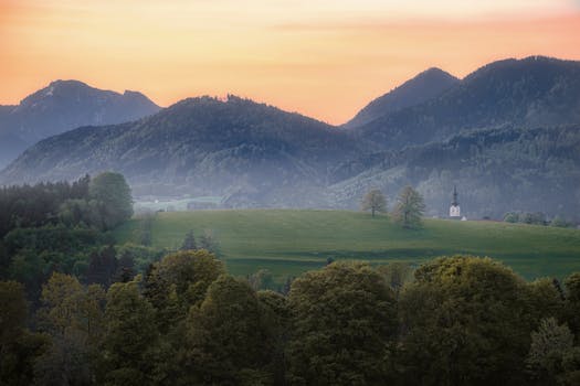 Stunning view of mountains and greenery under a warm sunrise sky, perfect for nature enthusiasts.
