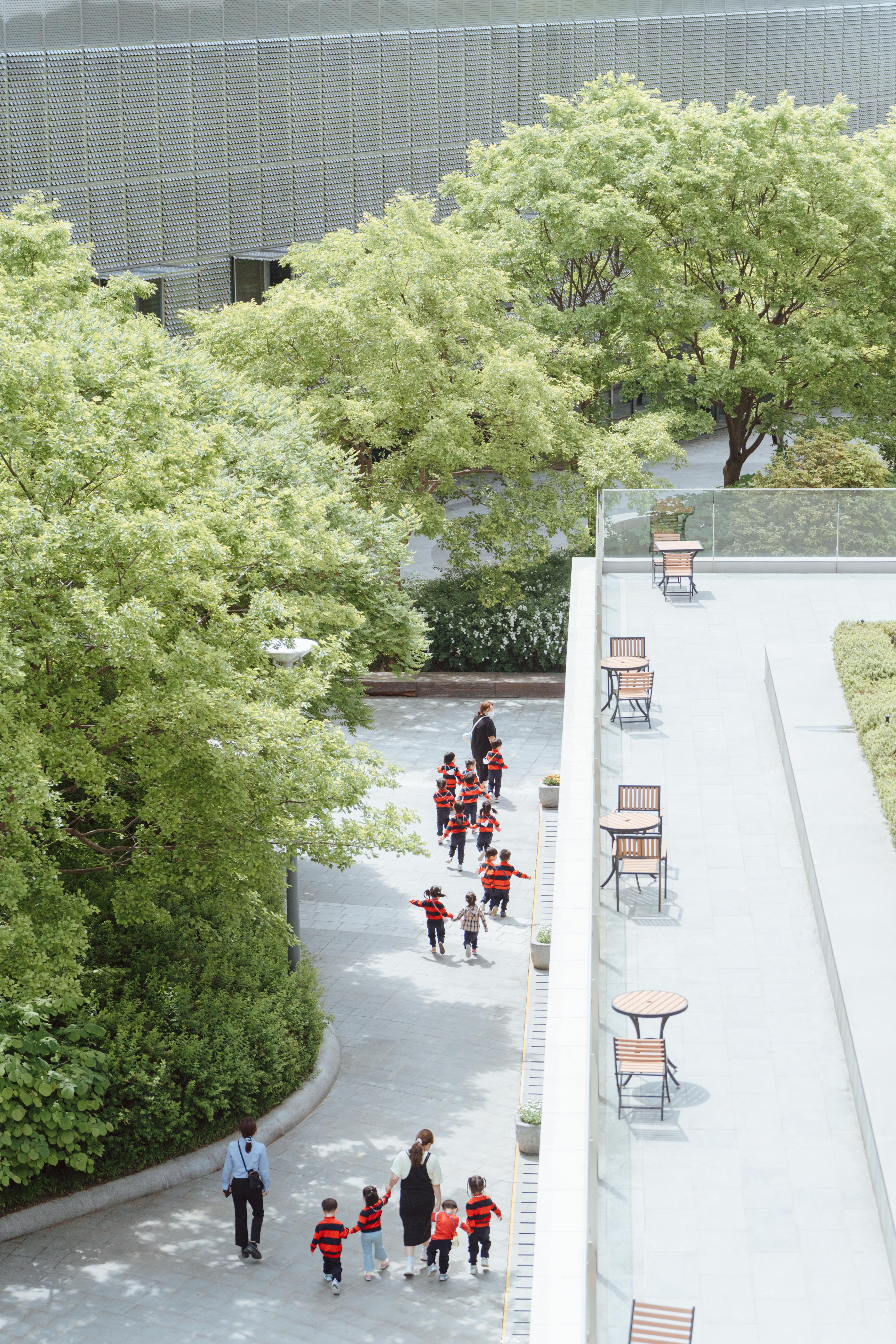 Group of children in red jackets on a school trip in an urban park setting.