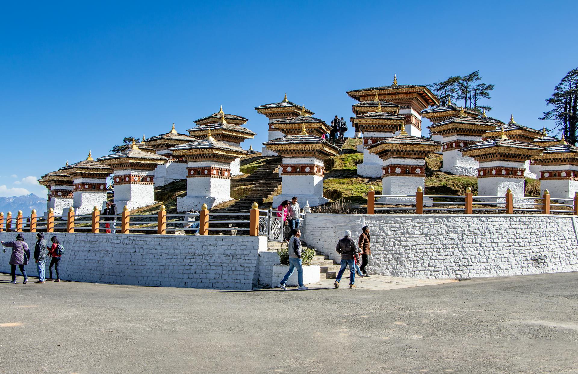 Scenic view of Dochula Pass featuring Druk Wangyal Chortens in Bhutan with tourists exploring.