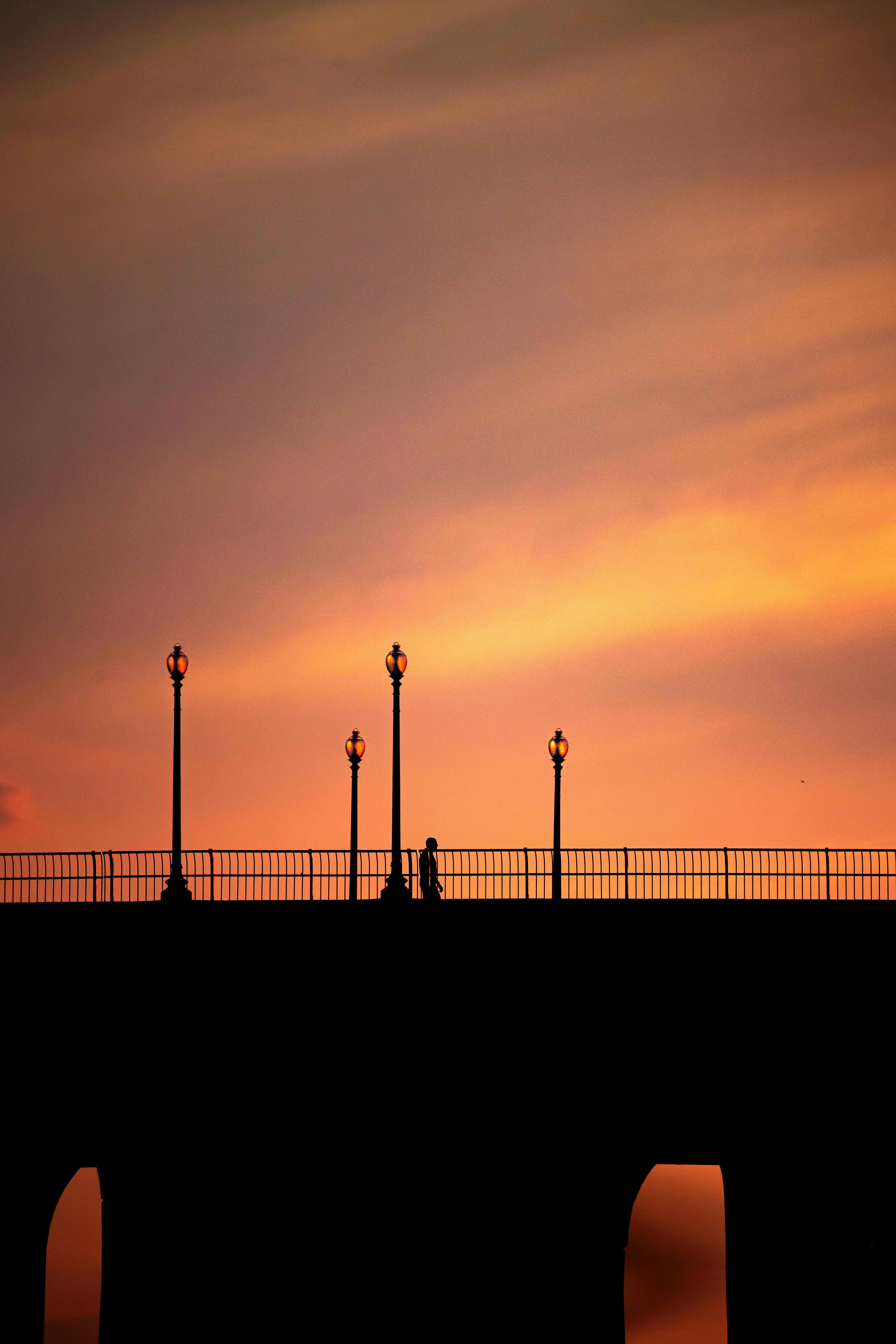 Stunning silhouette of a bridge and street lamps against a vibrant sunset in George Town, Penang.