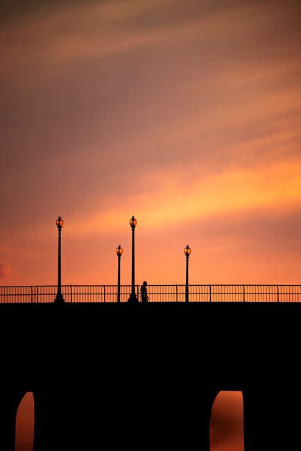 Stunning silhouette of a bridge and street lamps against a vibrant sunset in George Town, Penang.