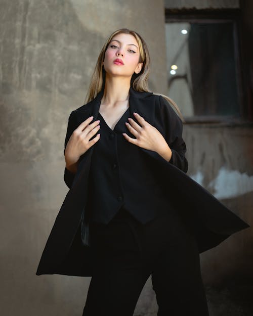 Photo of a Model Wearing Black Clothing, against a Concrete Wall