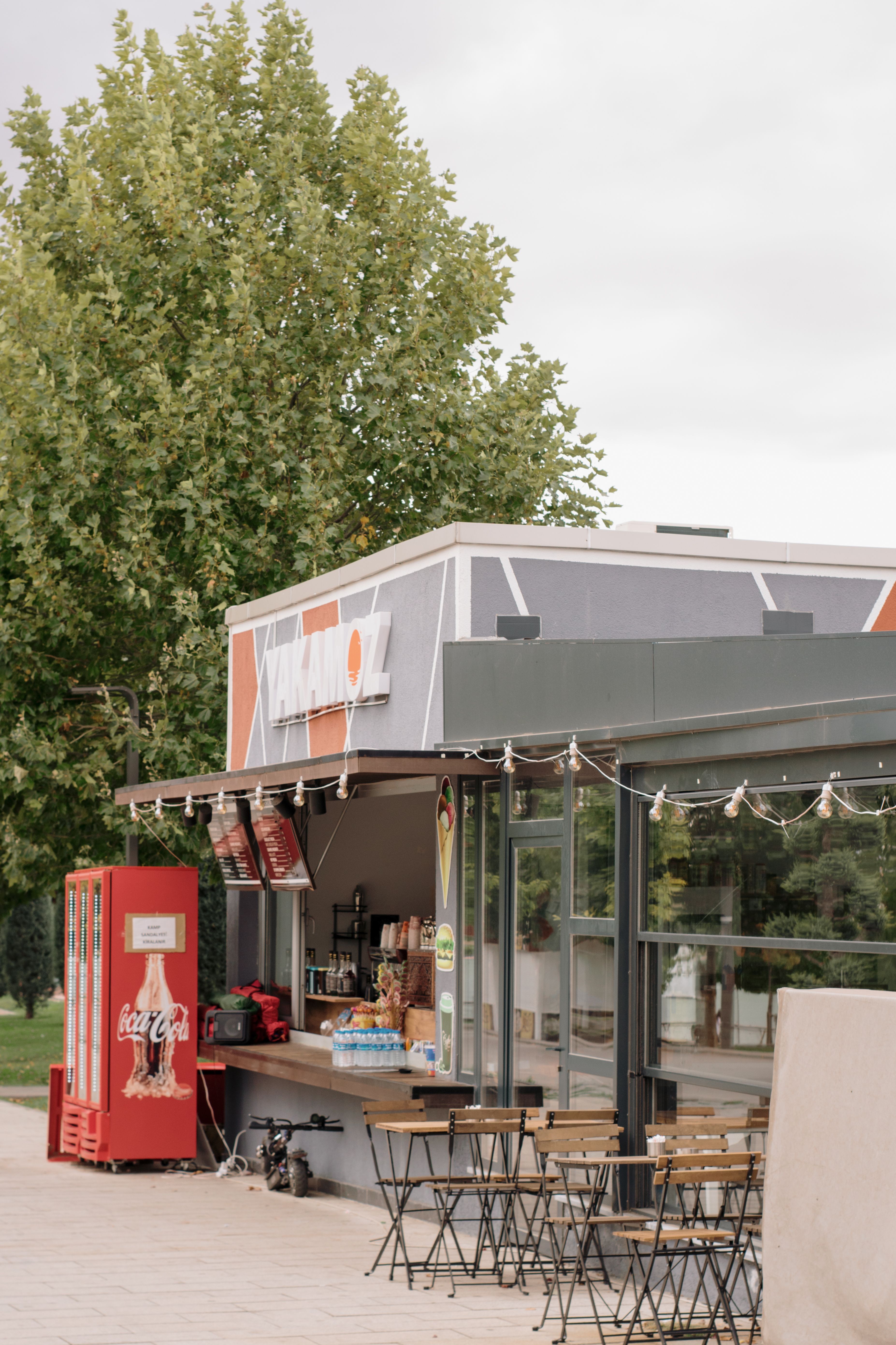 Modern food bar outdoors with seating and vending machine, perfect for a casual snack in the park.